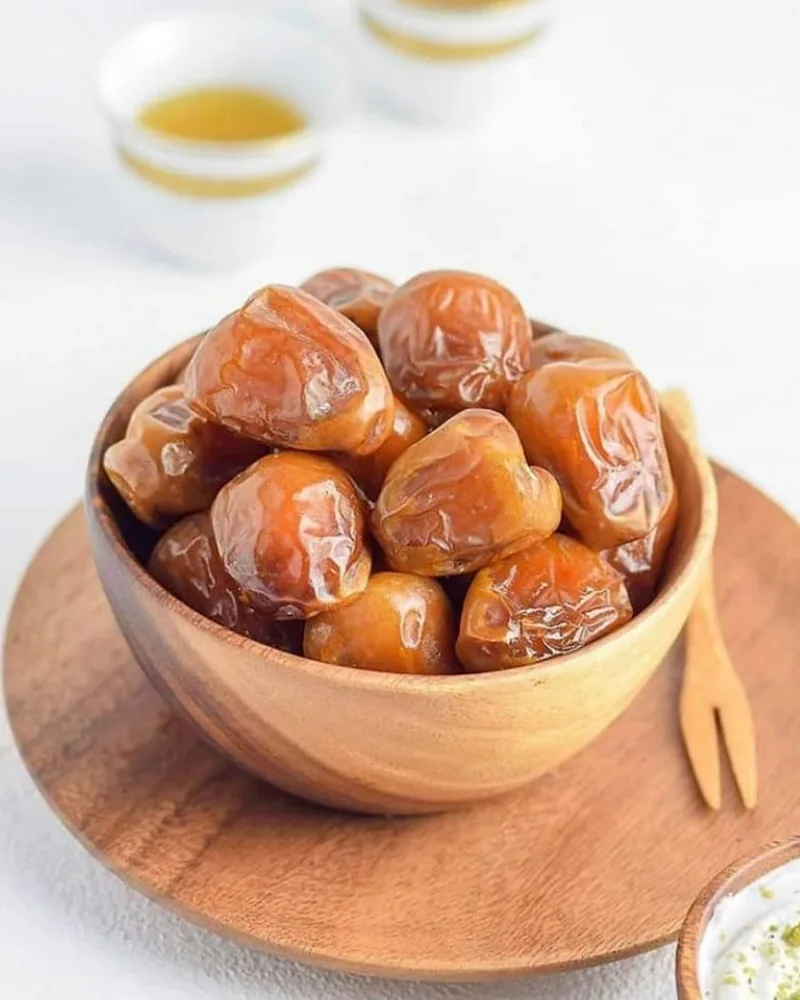 رطب السكري في صحن خشب، وخلفه فناجيل قهوة
